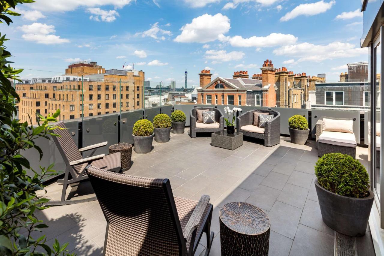 The May Fair, A Radisson Collection Hotel, Mayfair Londres Extérieur photo The photo depicts a spacious outdoor terrace or balcony. It features modern outdoor furniture, including comfortable seating arrangements with chairs and cushions. There are several planters with neatly trimmed greenery, adding a touch of nature to t
