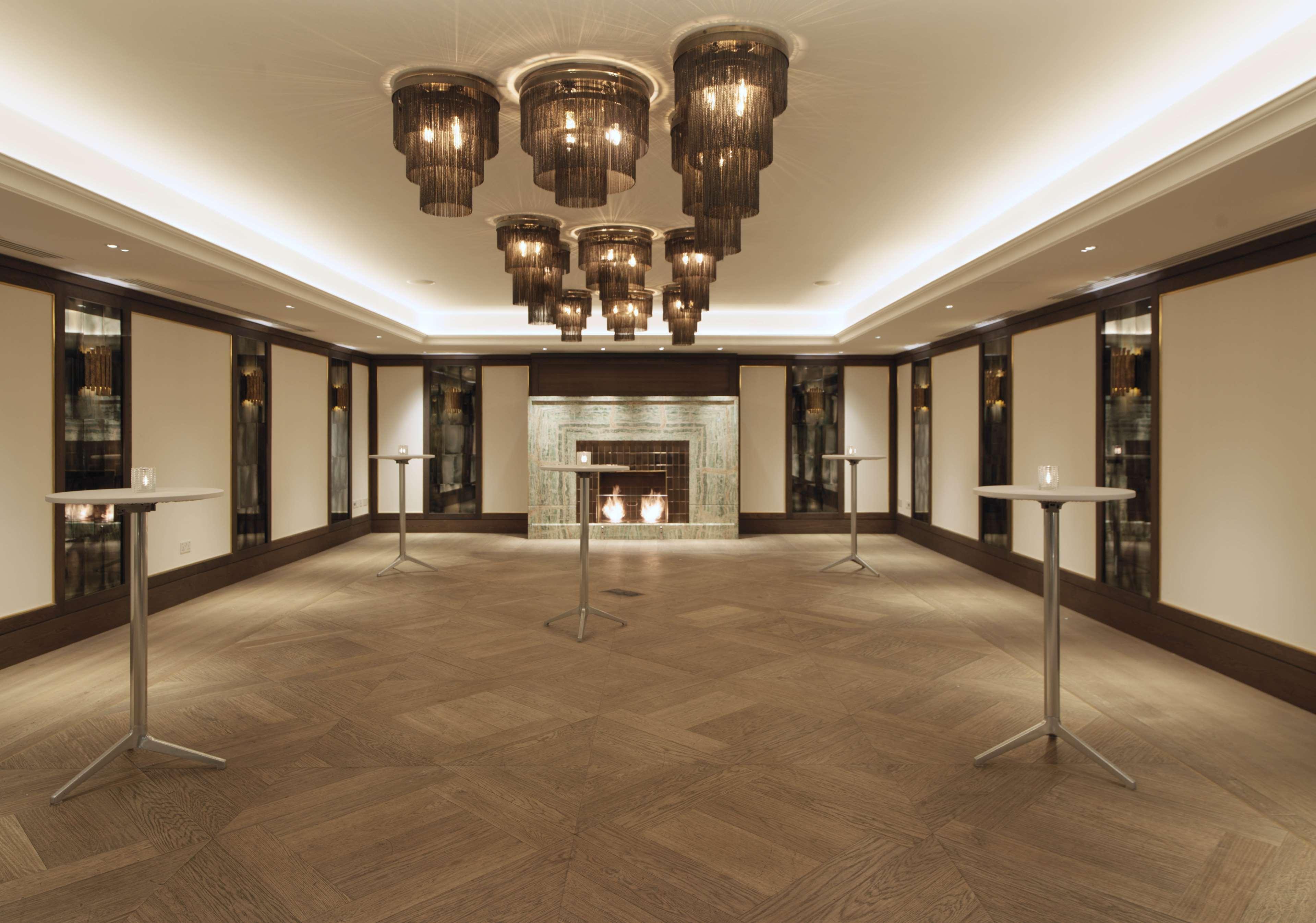 The May Fair, A Radisson Collection Hotel, Mayfair Londres Extérieur photo The photo showcases an elegant indoor space, likely designed for events or gatherings. The room features a sophisticated lighting arrangement with several modern pendant chandeliers hanging from the ceiling. There are minimalistic tall tables scatter