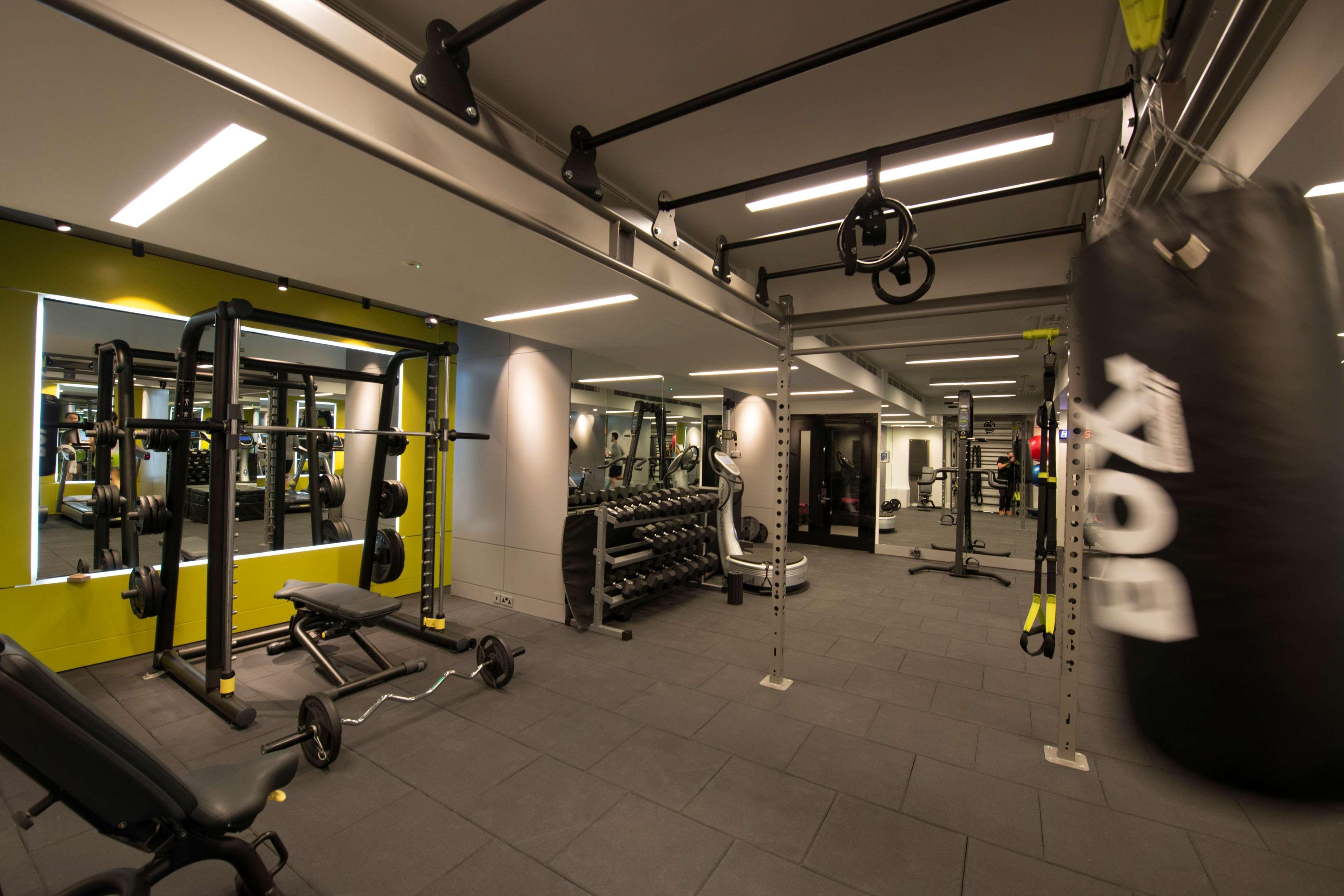The May Fair, A Radisson Collection Hotel, Mayfair Londres Extérieur photo The photo shows a modern gym interior. There are various fitness equipment pieces, including free weights, benches, and a multi-functional weight rack. The lighting is bright, with a mix of ceiling lights and mirrors on the walls that enhance the spa